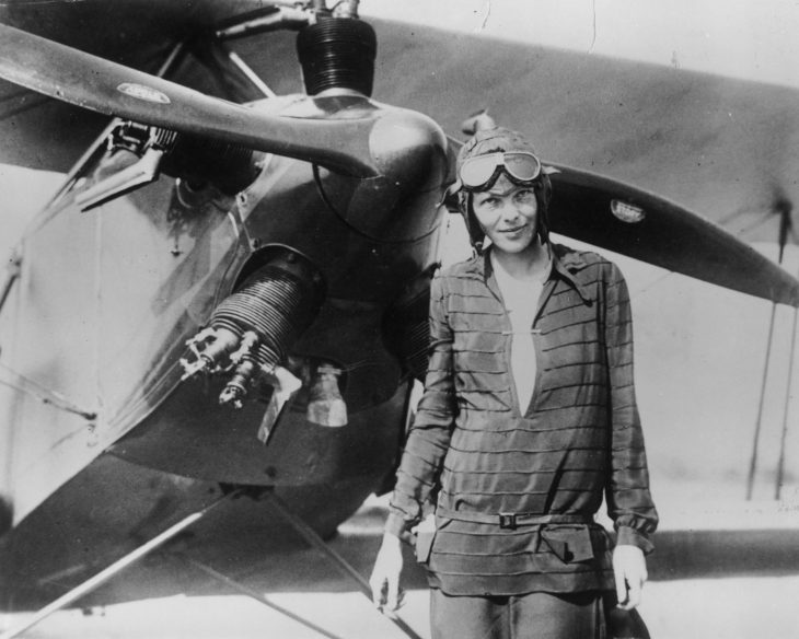 Amelia Earhart parada frente a un avión en el cual volaba