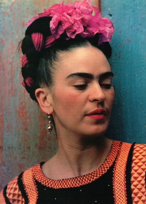 artista Frida khalo recargada sobre una pared de color azul 