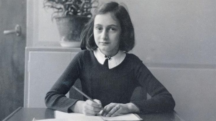 niña Ana frank sentada escribiendo en su diario 