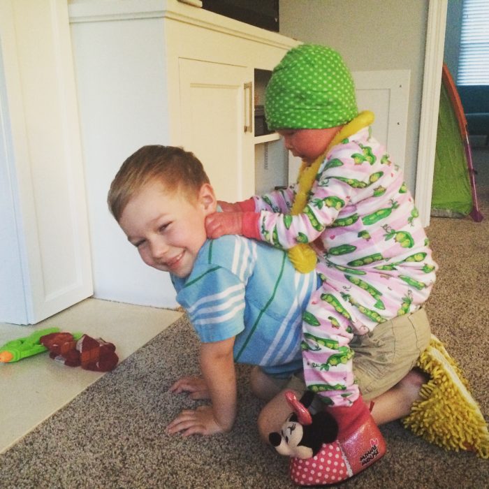 Niño cargando a su pequeña hermana en la espalda mientras juegan en una habitación