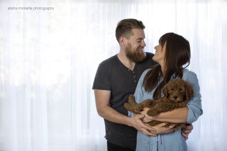 Pareja de novios sosteniendo en sus brazos a un cachorro 