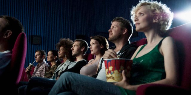 Personas viendo una película en una sala de cine mientras comen palomitas 