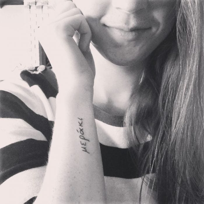 Chica con un tatuaje de la frase meraki en si brazo 