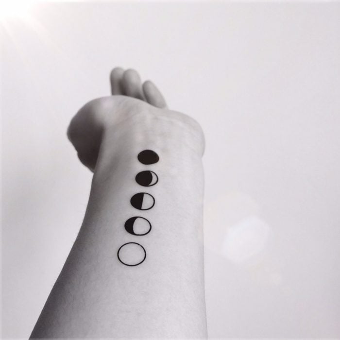 Brazo de una chica con un ciclo lunar tatuado 