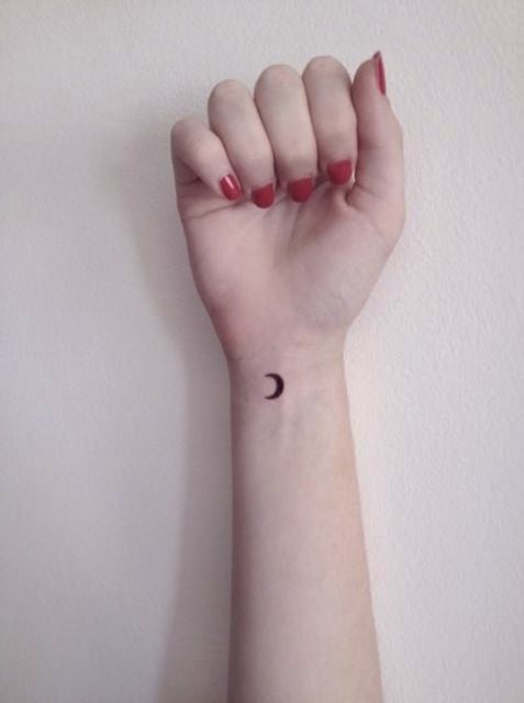 Mano de una chica con un tatuaje de una pequeña luna en su muñeca