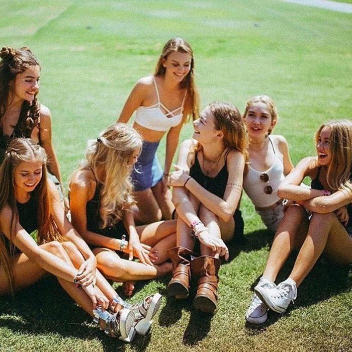 Amigas sentadas en el pasto conversando 