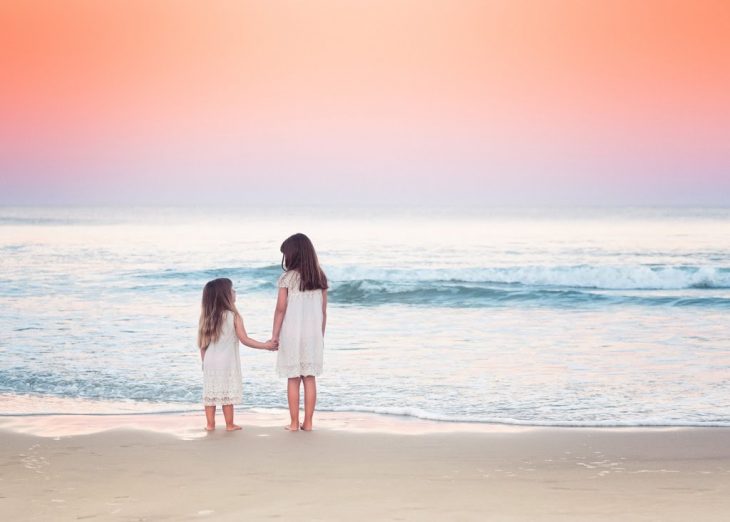 Hermanas abrazadas en la paya viendo el mar 