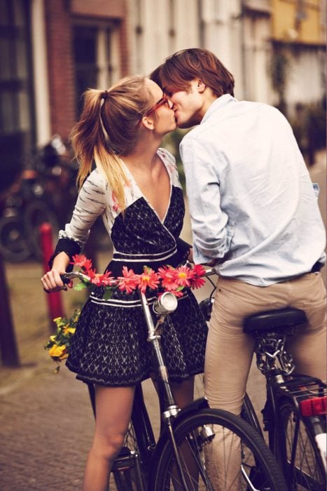 hombre en una bicicleta besando a una chica que también está en bicicleta 
