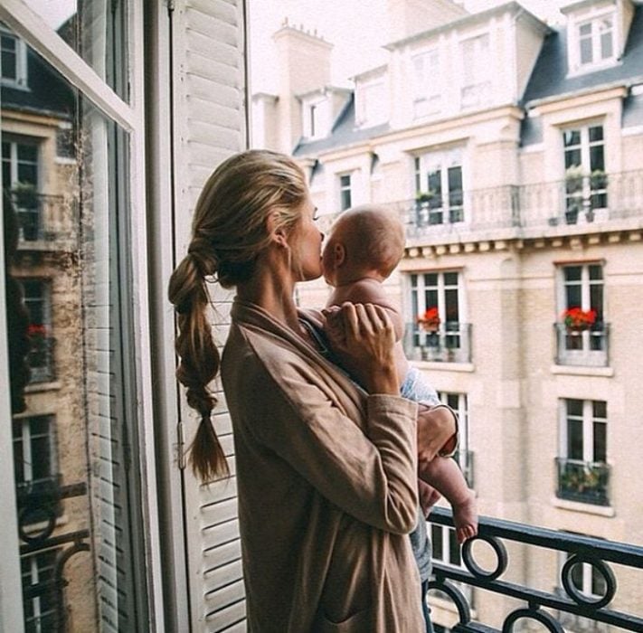 mujer sosteniendo a su bebé mientras están en el balcón 