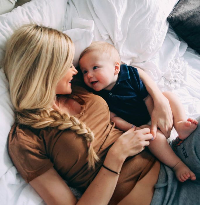 Mamá recostada en la cama junto a su bebé