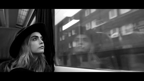 GIF Cara Delevinge viajando en tren mientras mira por la ventana 