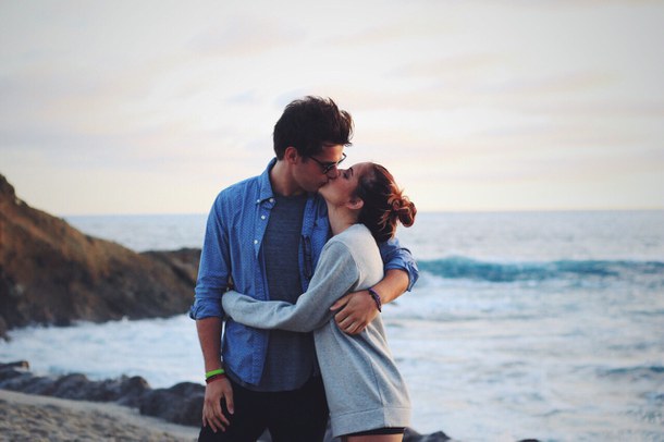Chica besando a un chico mientras están en la playa 