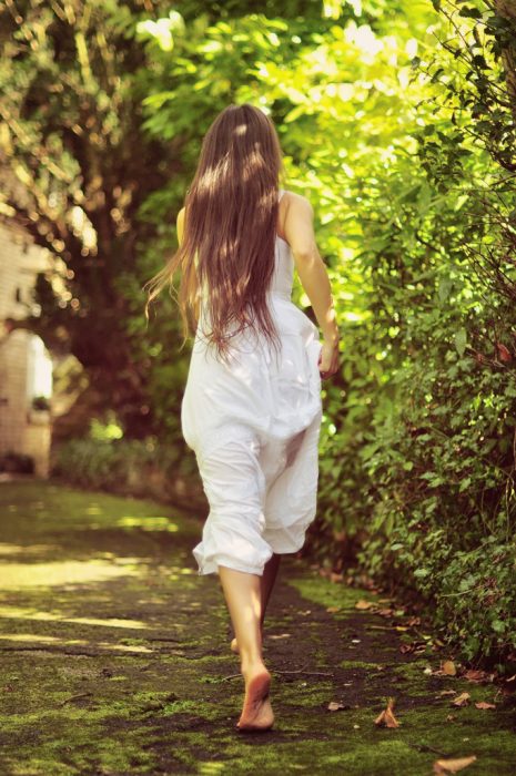 Chica corriendo a través de un jardín 