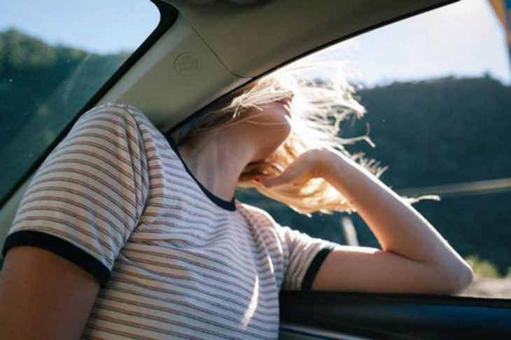 chica sacando la cabeza por la ventana de un coche