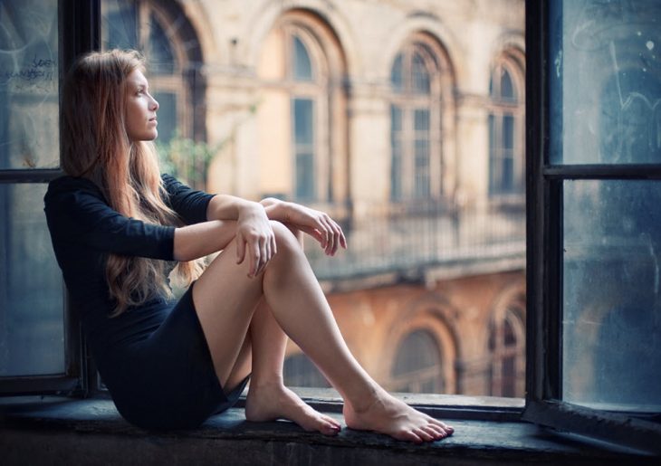 Chica sentada en una ventana pensando 