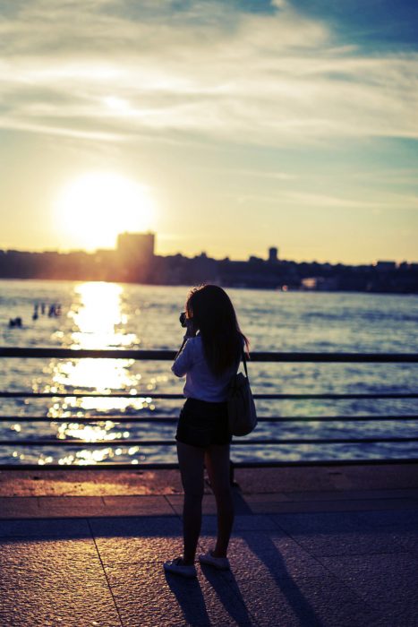 chica tomando fotografías a un atardecer