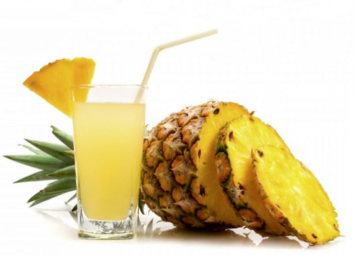 Jugo de piña junto a una piña natural 