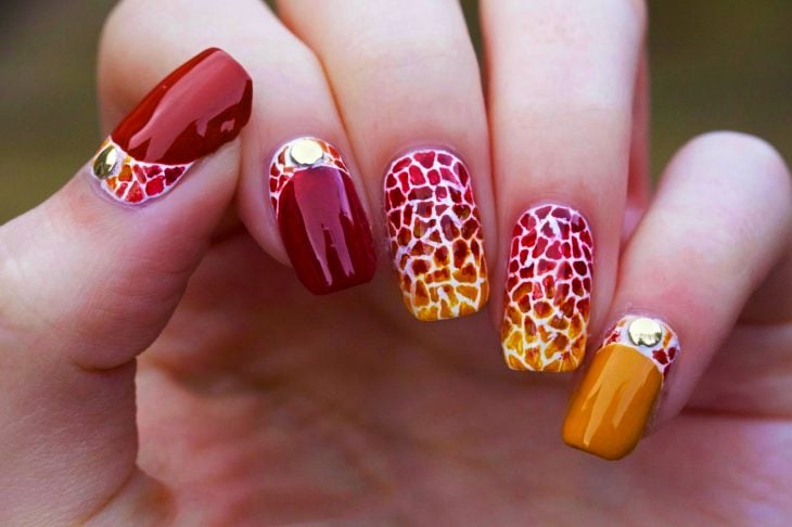 Uñas pintadas con diseños en rojo y naranja 