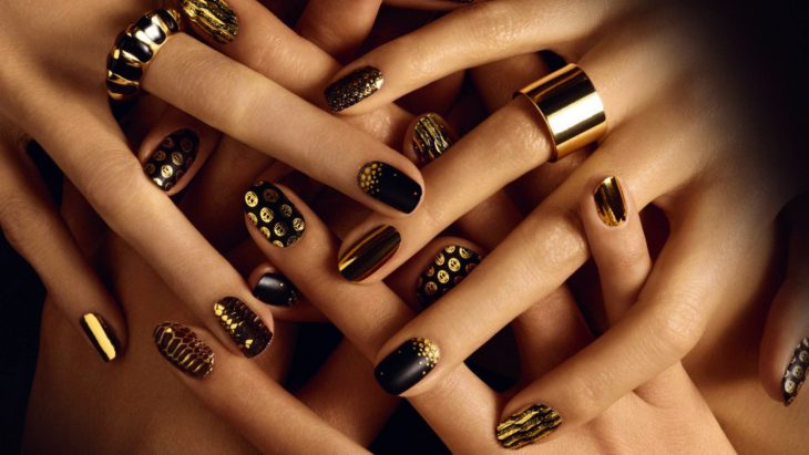 Uñas pintadas con esmalte en color negro y dorado 