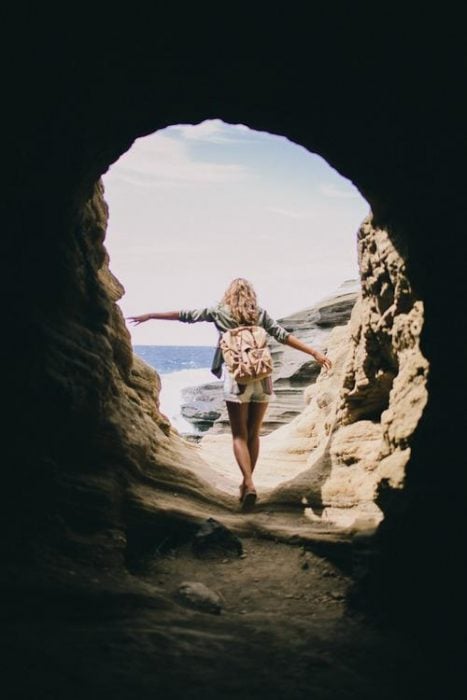 Chica atravesando una cueva que da hacia el mar 