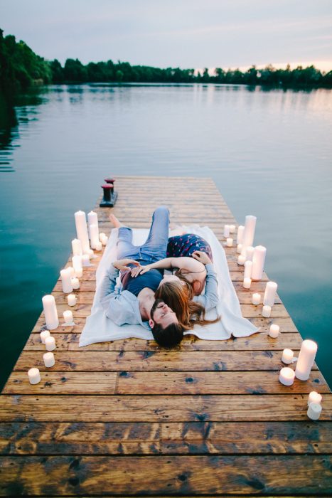 Pareja de novios recostados en un muelle con velas a su alrededor 