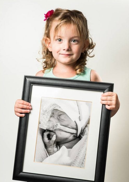 niña sosteniendo su fotografía de cuando nacio como una bebé prematura