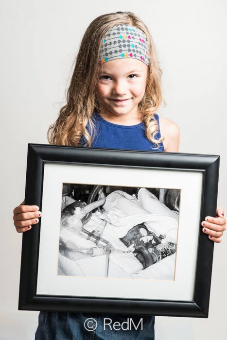 Niña sosteniendo una foto de ella misma ciuando estaba recien nacida