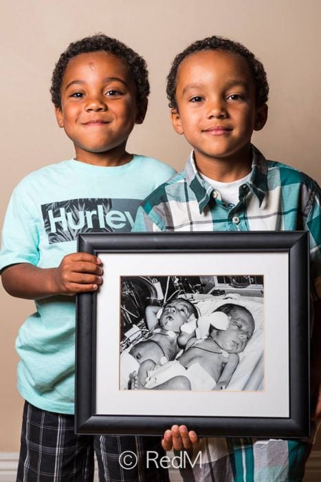 hermanos gemelos sosteniendo una fotografia de ellos cuando eran bebés