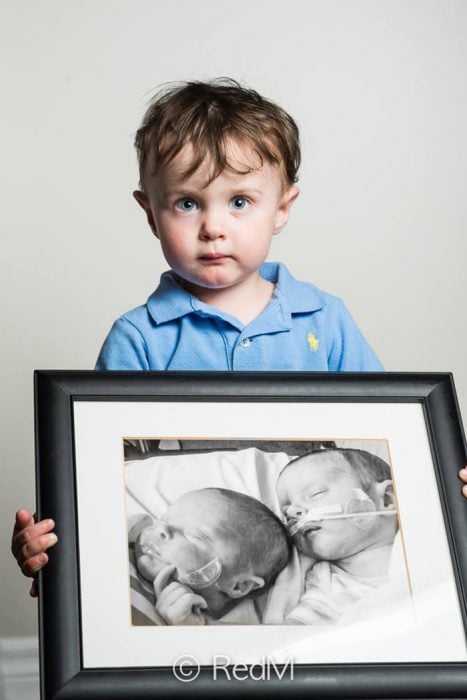 niño sosteniendo una fotografía de él y de su hermana cuando eran bebes prematuros