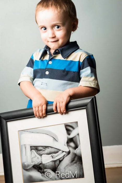 Niño sosteniendo una imagen de él cuando era un bebé que estaba en la incubadora