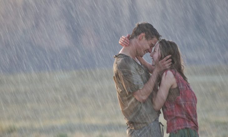 Pareja de novios besándose bajo la lluvia