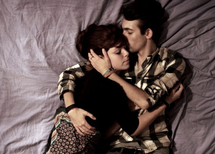 Pareja de novios recostados en una cama abrazados 