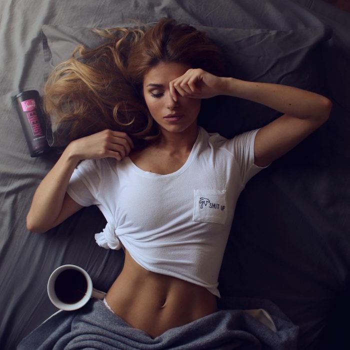 Chica recostada en una cama tomando café 