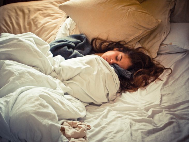 Chica con el cabello revuelto durmiendo en una cama 