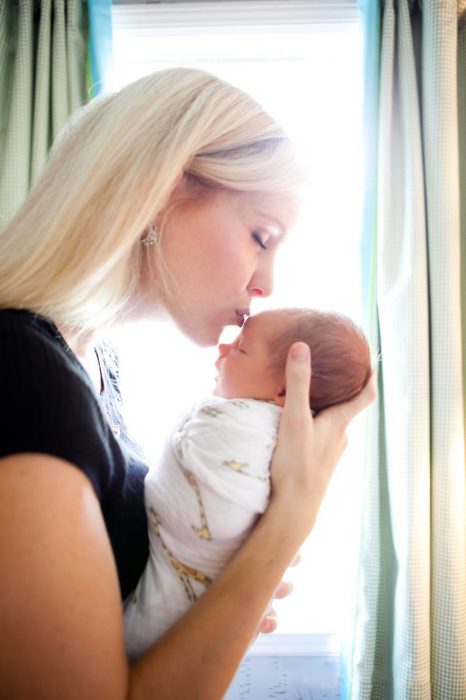 mujer besando a un bebé en la frente 