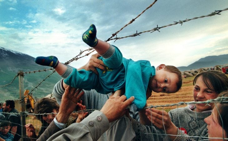 niño refugiado es pasado entre púas de alambre