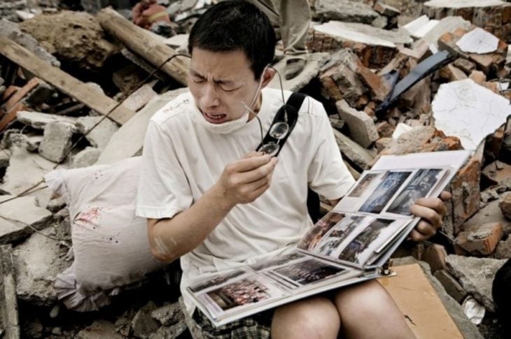 Hombre chino llora al ver album de fotos frente a las ruinas de su casa