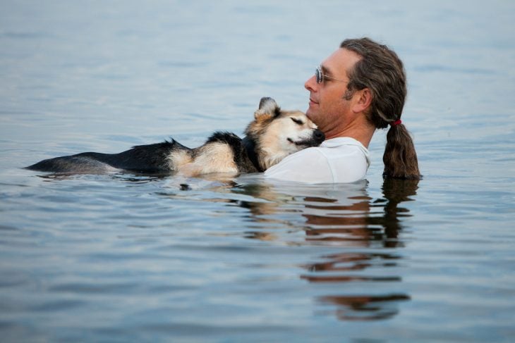hombre baña a su perro artrítico en lago