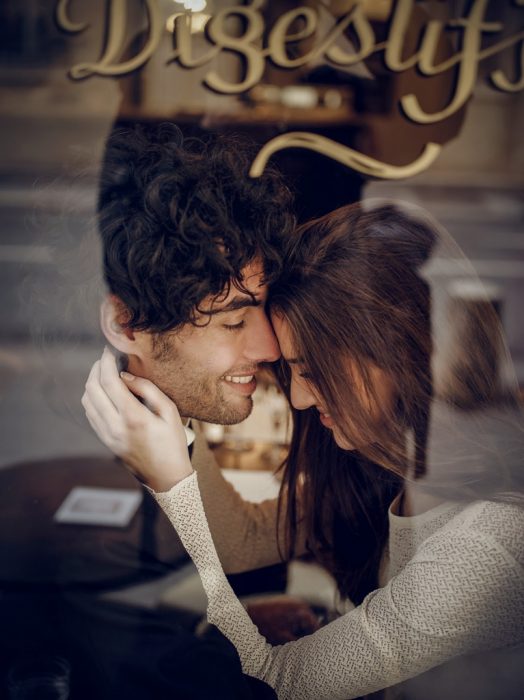 Pareja de novios en un café sentados besándose 