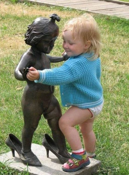 Niña intentando bailar con una estatua en forma de niña