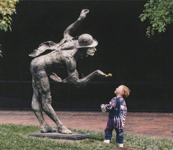 Niño viendo con curiosidad una estatua
