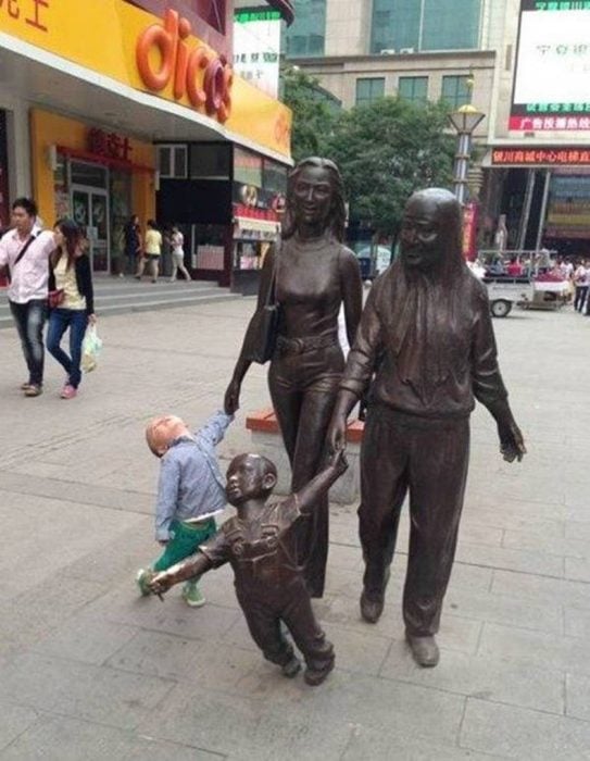 Niño tomando de la mano a una estatua que piensa que es su mamá