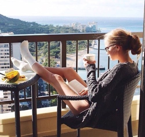 chica sentada en balcón leyendo