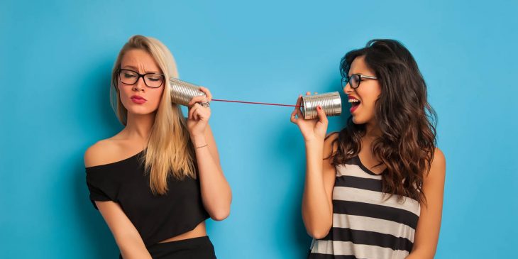 Chica hablando con otra a través de dos latas con un cable 