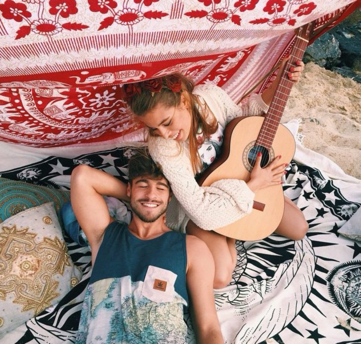 Pareja tocando la guitarra en la playa 