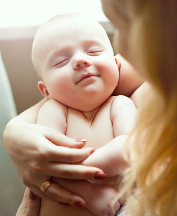 Bebé durmiendo en los brazos de su mamá 