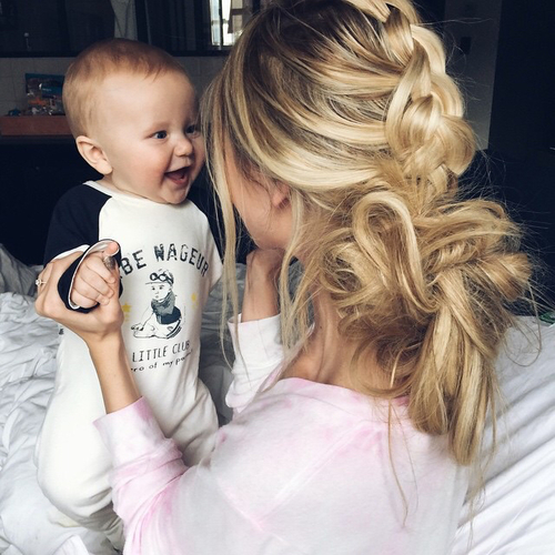 Mamá junto a su bebe riendo mientras están en la cama 