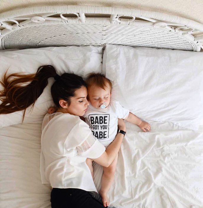 Mamá durmiendo junto a su bebé en la cama 