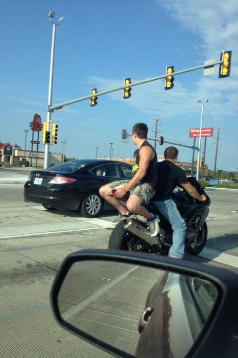 Hombre sentado en la parte de atrás de una motocicleta, pero viendo al frente