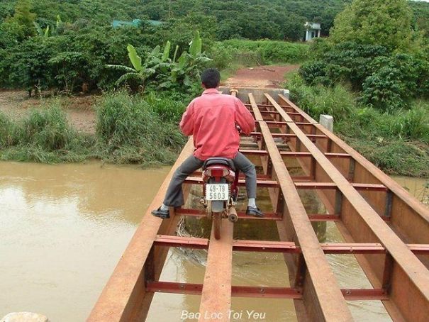 Hombre cruzando un puente con su motocicleta